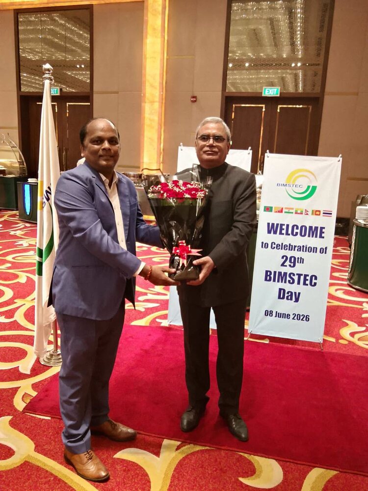 Rahul Laxman Patil presenting a bouquet at the celebration of the 29th BIMSTEC Day, with the BIMSTEC banner and member-state flags behind.