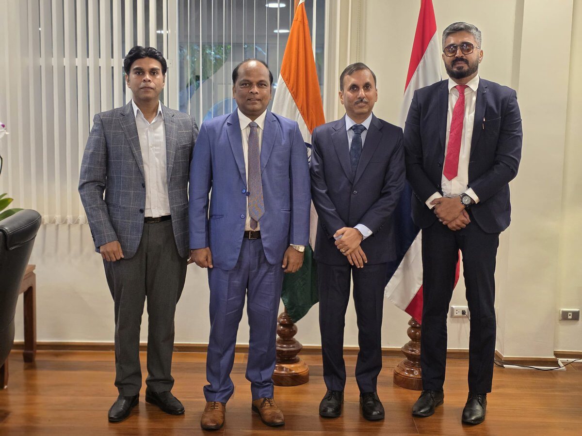 Rahul Laxman Patil with a diplomatic delegation standing before the Indian national flag and a partner nation's flag at a mission office.