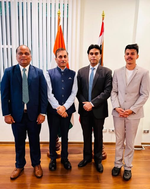A four-member delegation including Rahul Laxman Patil photographed together beside national flags after a briefing.